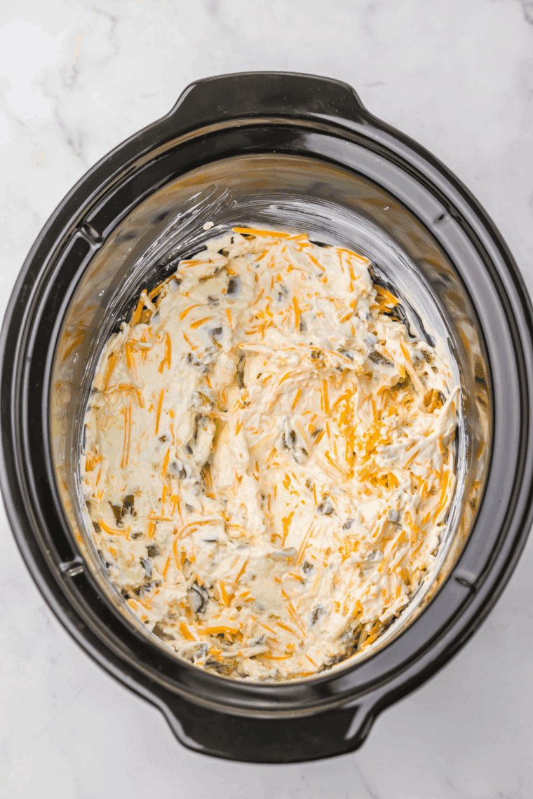Creamy jalape&ntilde;o popper dip cooking in slow cooker, being stirred