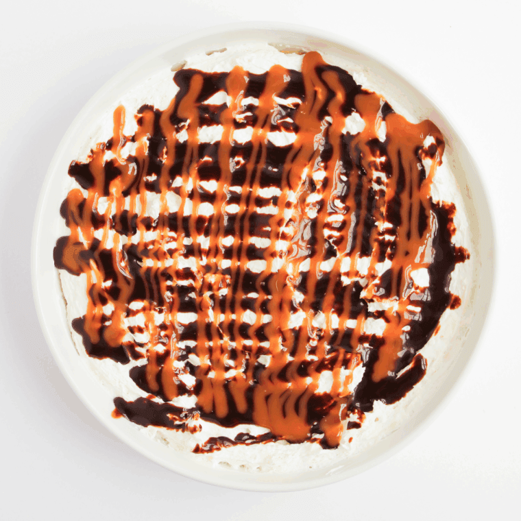 Layering cheesecake filling on crust, drizzling caramel and chocolate, sprinkling chocolate and pecans.