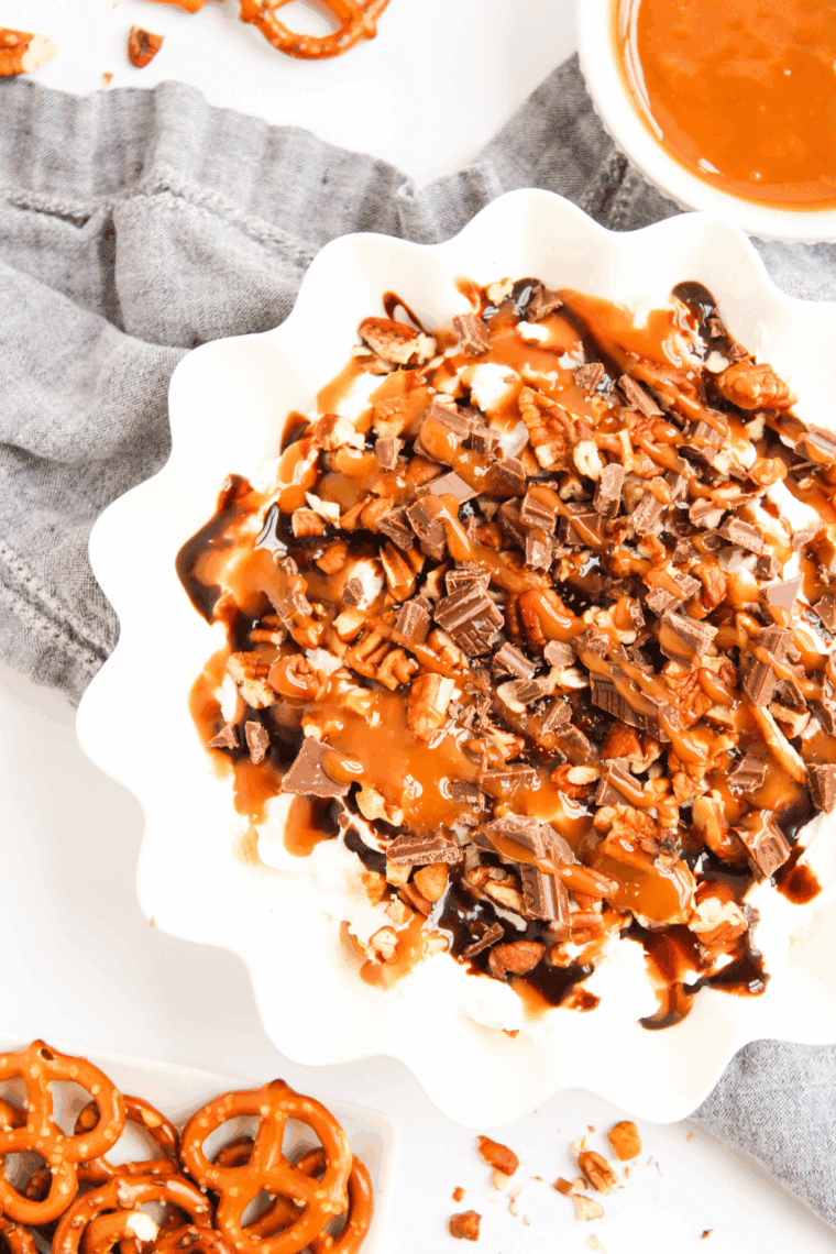 Easy Turtle Cheesecake Dip in a bowl with caramel drizzle, chocolate pieces, and chopped pecans, ready for serving with crackers and fruit.