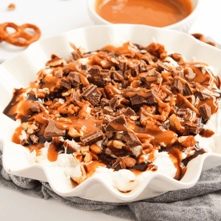 Turtle Cheesecake Dip served in a bowl, topped with caramel drizzle, chocolate chunks, and chopped pecans, ready for dipping.