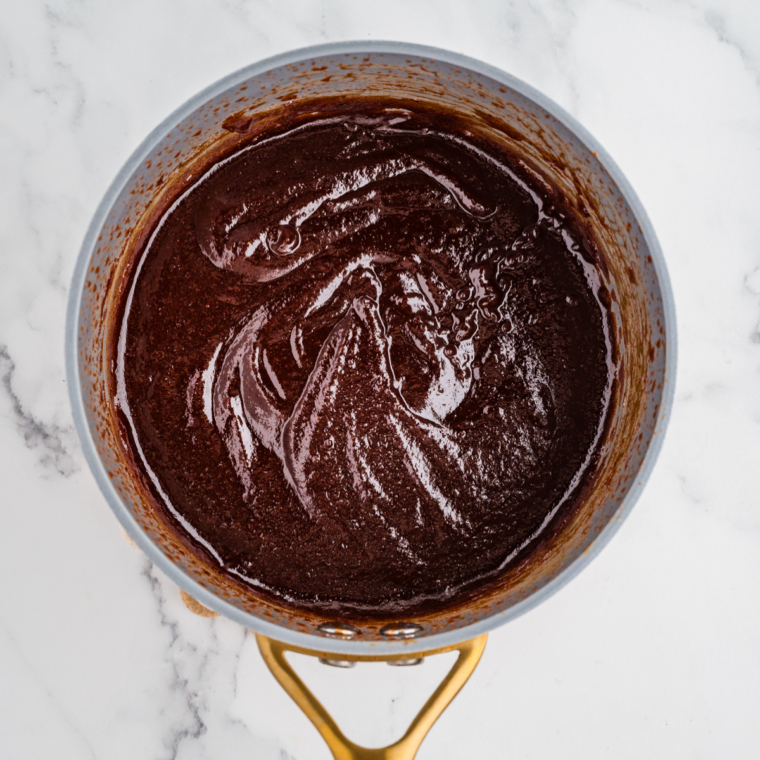 Hot honey BBQ sauce in a saucepan after cooking, darkened and thickened to a glossy finish