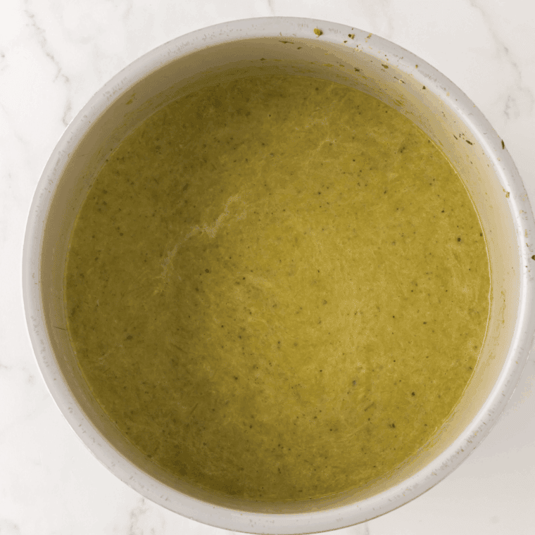 Thick heavy cream being stirred into the blended green soup inside the Ninja Foodi pot to create a rich, velvety finish.