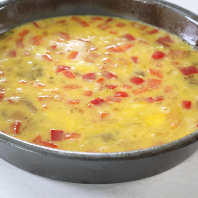 Lightly greasing silicone egg bite molds and pouring in egg mixture