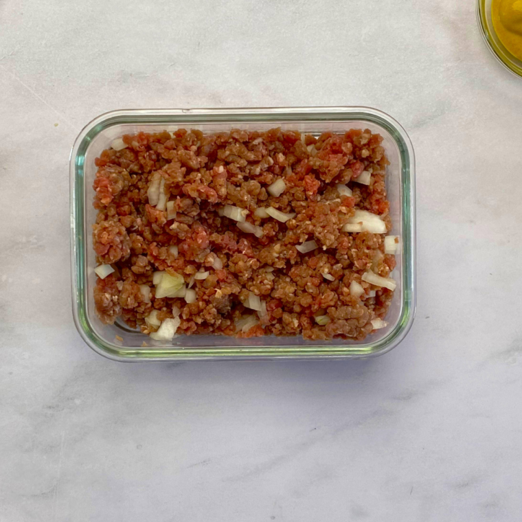 Mixing ground beef, chopped onion, Worcestershire sauce, salt, and pepper in a bowl before air frying at 375&deg;F (190&deg;C).