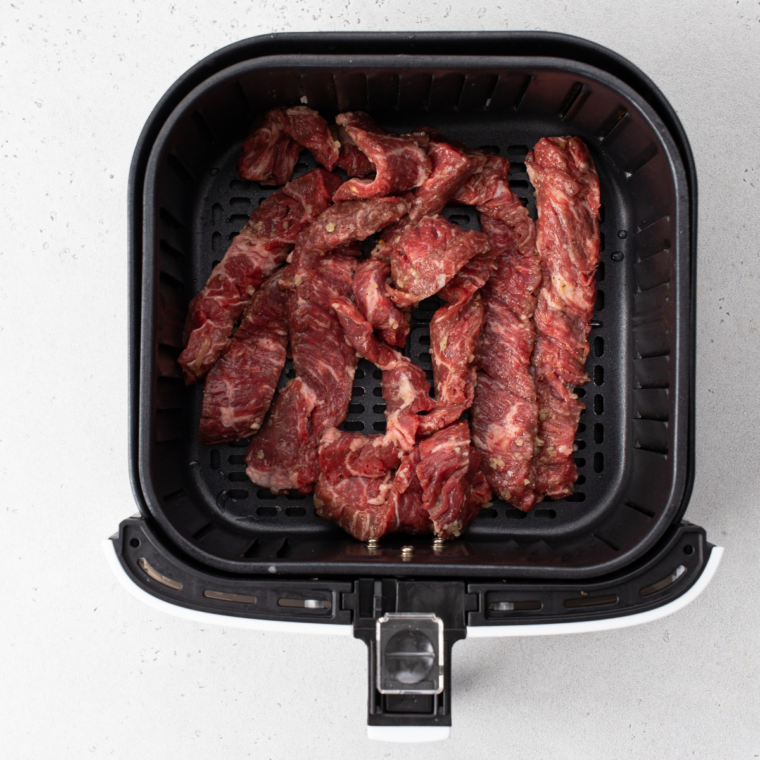 Beef, bell pepper, water chestnuts, and shredded carrots cooking in the air fryer