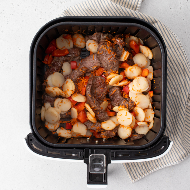 Finished beef lo mein plated with sesame seeds and diced green onions on top