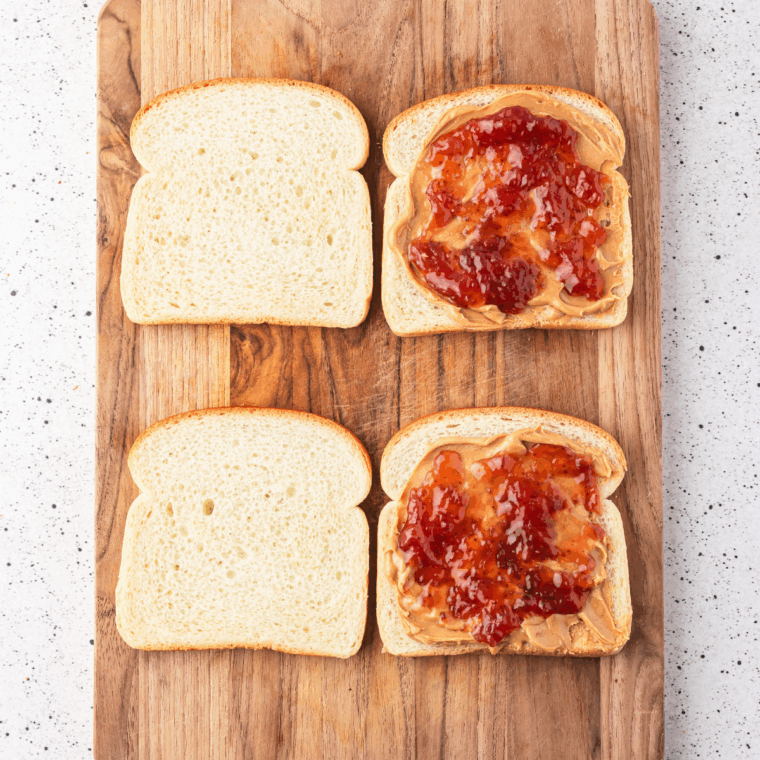 Spreading peanut butter and jelly on bread slices with optional fillings.