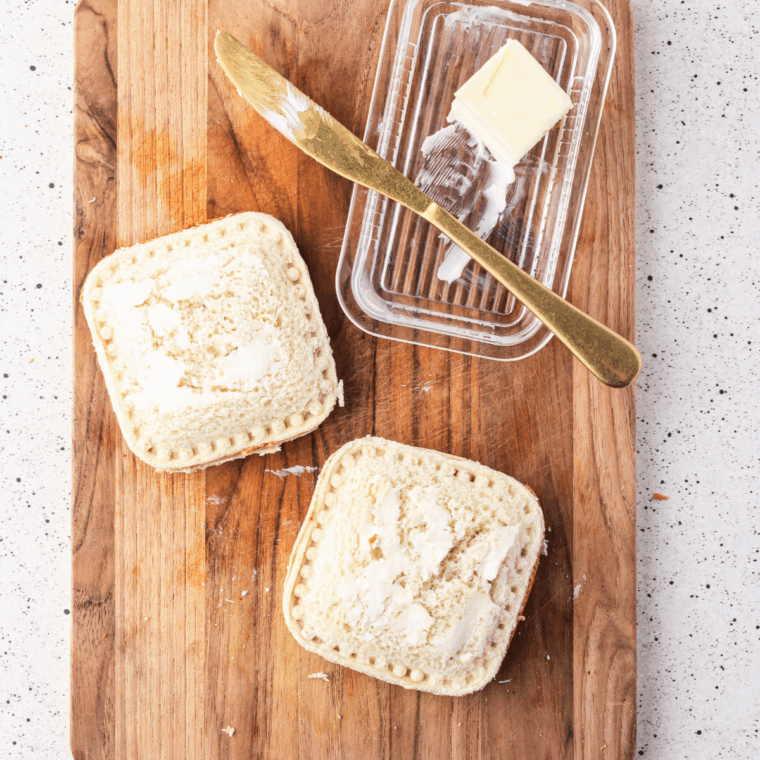 Sealed DIY Uncrustables in air fryer basket, brushed with butter and cooking spray, cooking until golden