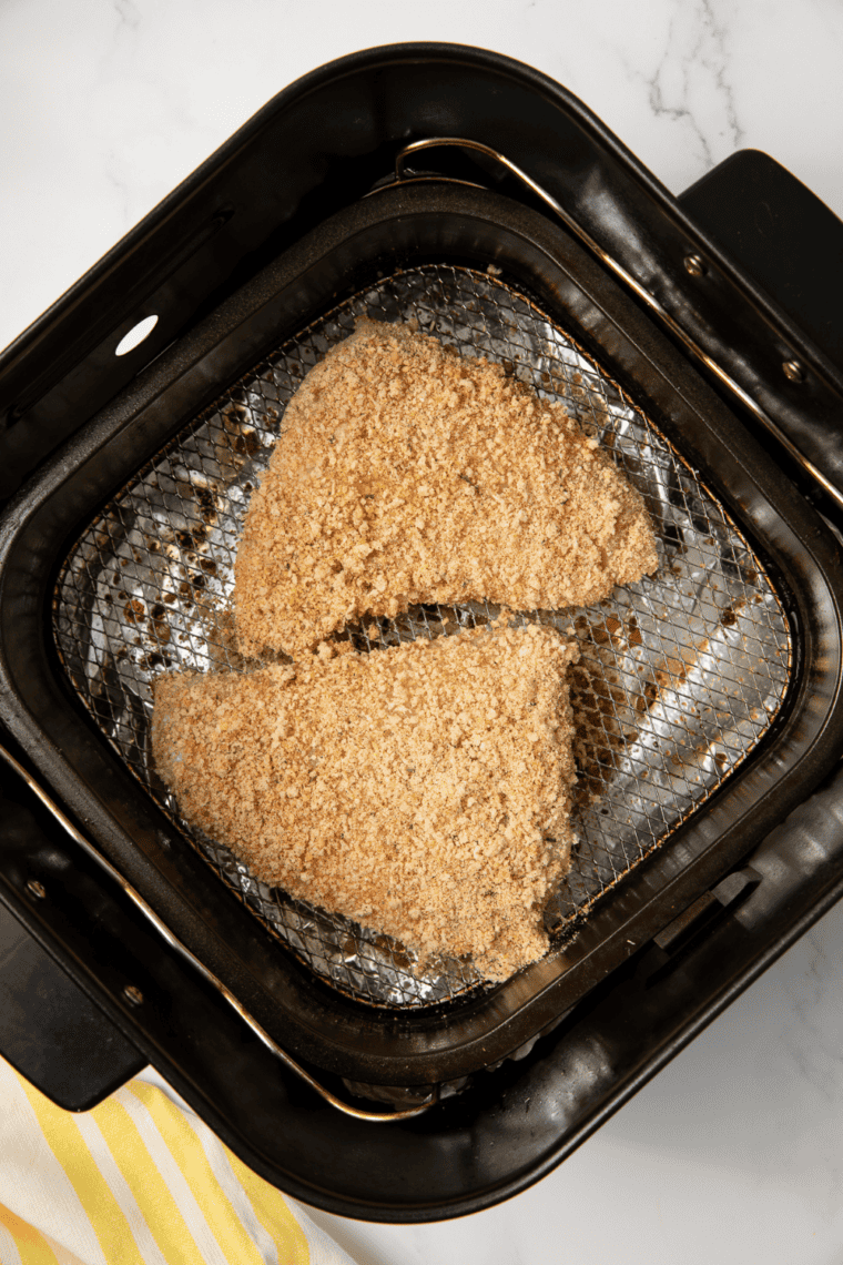 Panko crusted red snapper fillets cooking in air fryer basket until golden brown