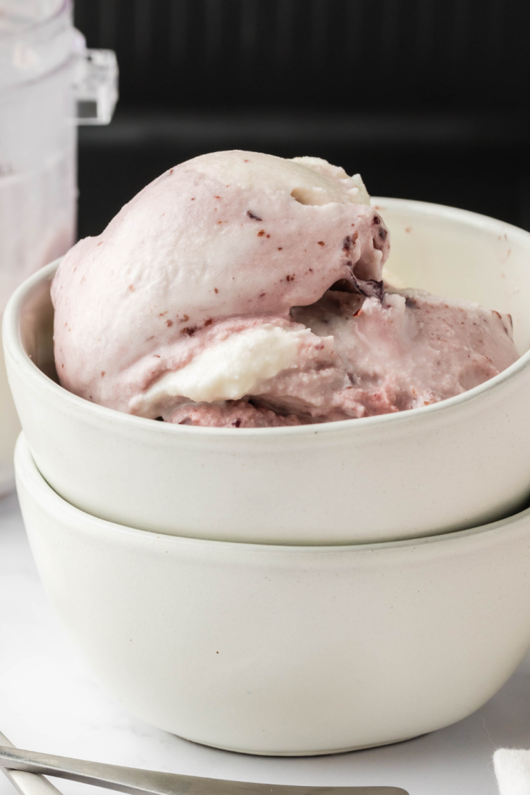 Homemade cherry gelato in a bowl, smooth and creamy, topped with fresh cherries, made using the Ninja Creami.