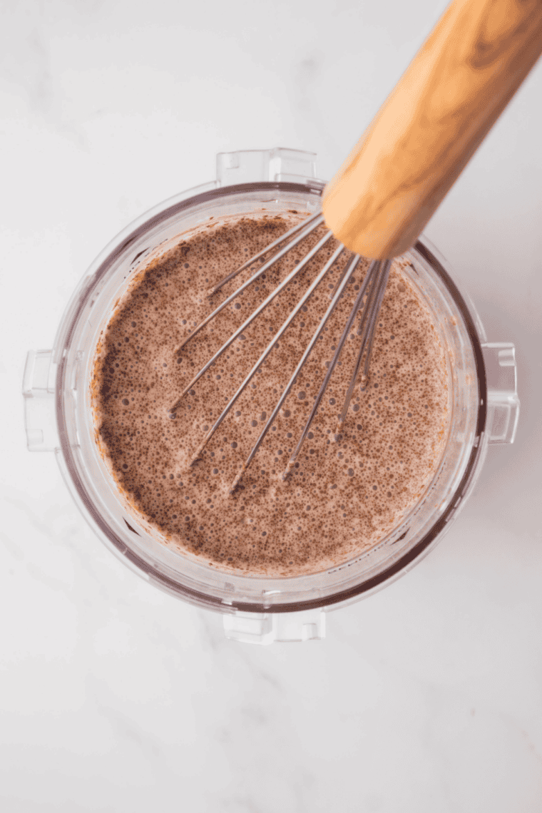 Whisking milk, heavy cream, sugar, cocoa powder, and milk powder together in a bowl to make chocolate gelato base.