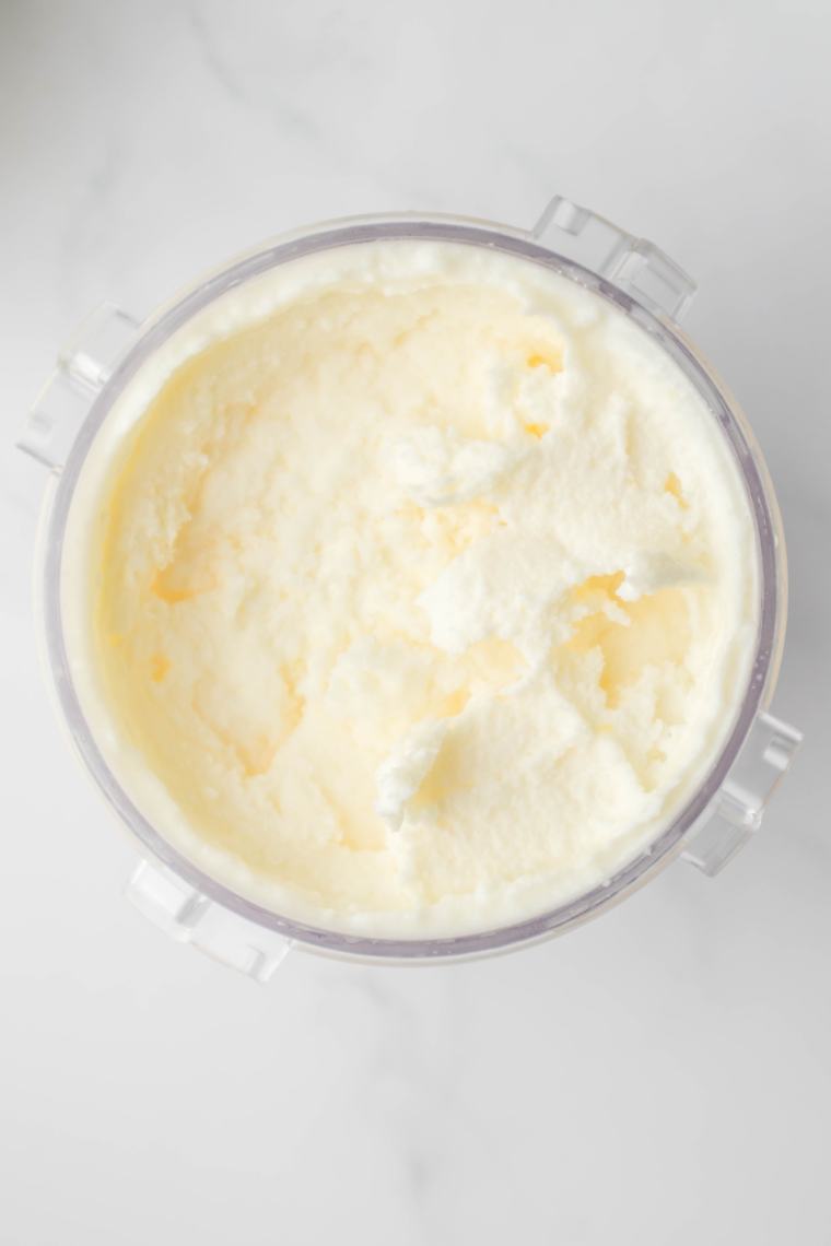 Creamy, bright yellow lemon gelato made in the Ninja Creami, served in a bowl with lemon zest on top.