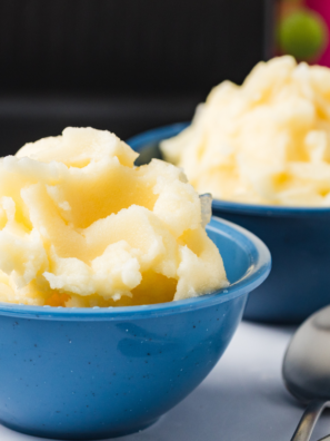 Scoop of creamy homemade lemon gelato made in the Ninja Creami, served in a bowl with fresh lemon slices.