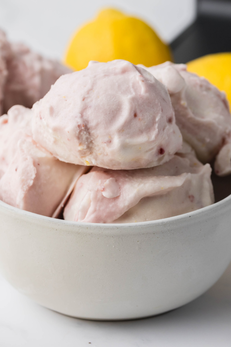 Creamy lemon raspberry gelato served in a bowl with fresh raspberries and lemon zest, made using the Ninja Creami