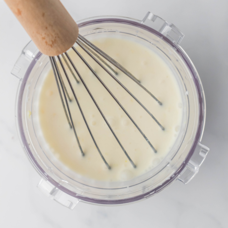 Lemon gelato mixture poured into a Ninja Creami pint container, ready for freezing
