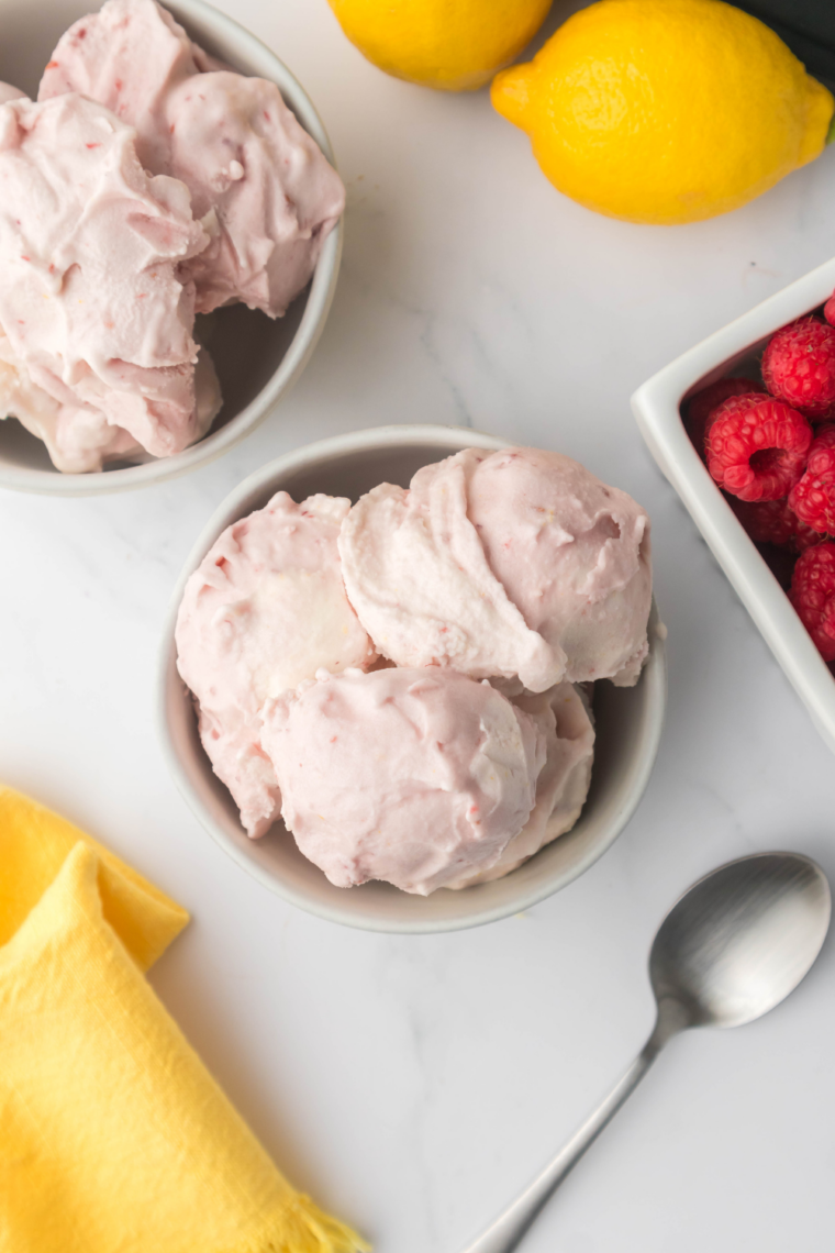 Creamy lemon raspberry gelato in a bowl garnished with fresh raspberries and lemon zest, made using the Ninja Creami