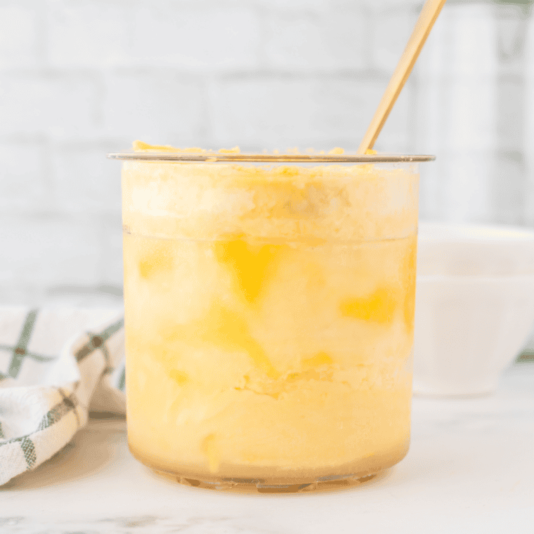 Blending ripe mangoes, milk, heavy cream, sugar, and lime juice in a bowl until smooth.