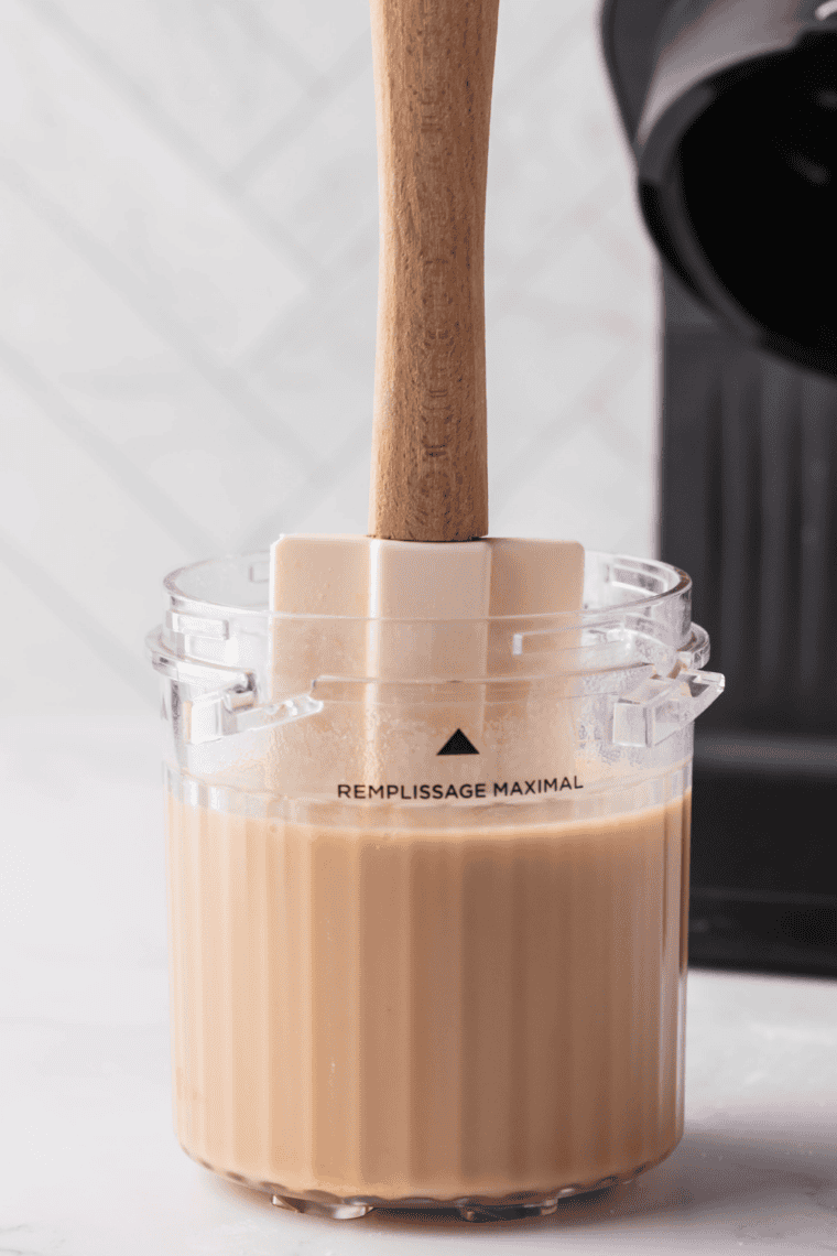 Ninja Creami pint filled with vanilla iced coffee mixture placed upright in freezer.