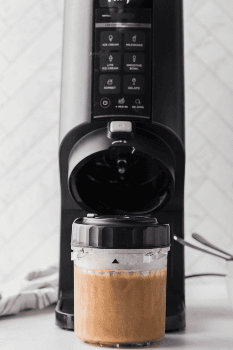 Frozen vanilla iced coffee pint inserted into Ninja Creami machine on Lite Ice Cream setting.