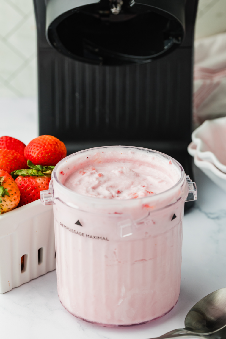 Homemade strawberry gelato scooped into a bowl, made in the Ninja Creami and topped with fresh strawberry pieces.