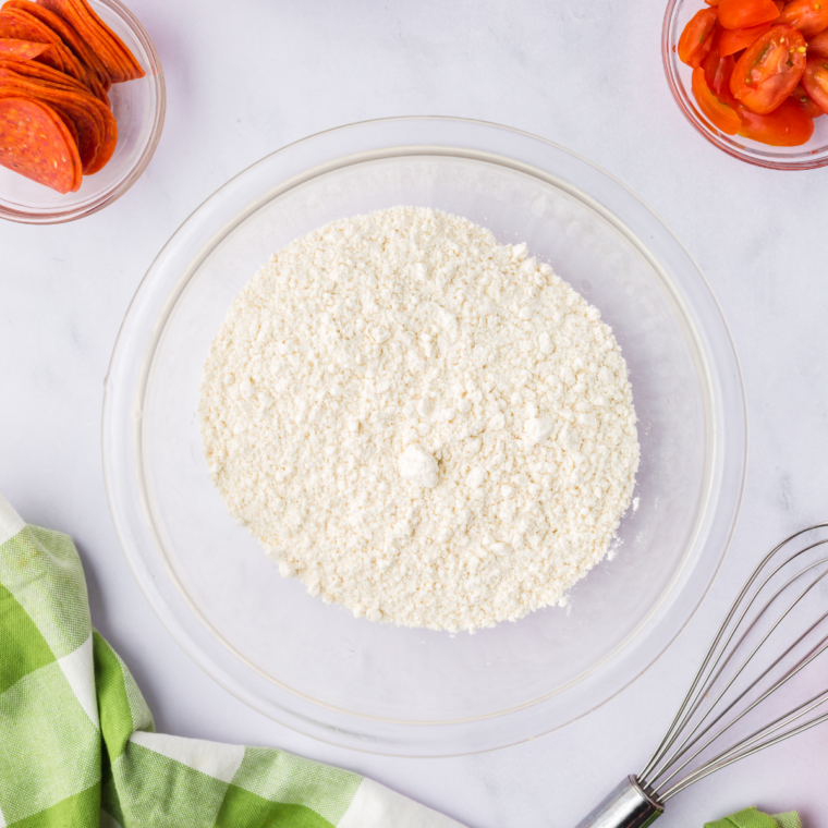 Food processor with high-protein flour, instant yeast, and water forming a rough pizza dough ball.