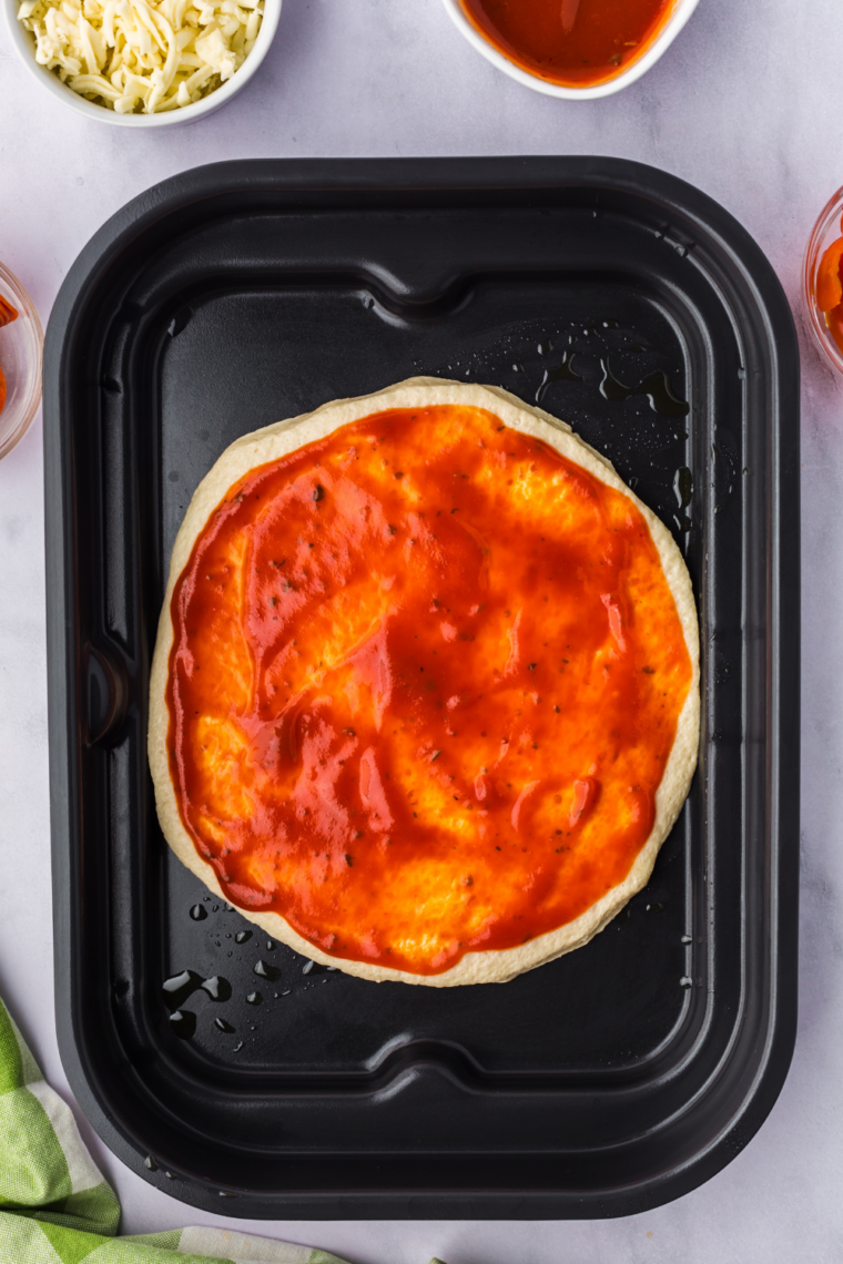 Dough being stretched into pizza bases, topped with sauce, cheese, and ingredients.