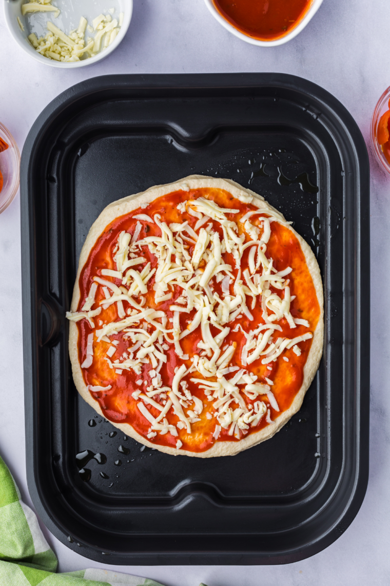 Pizza cooking on Ninja Woodfire Grill, crust turning golden, cheese bubbling.