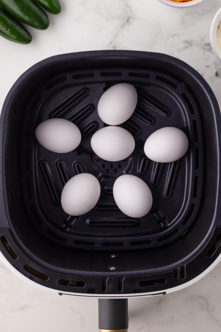 Prepare the Eggs: Large eggs arranged in a single layer in the air fryer basket.