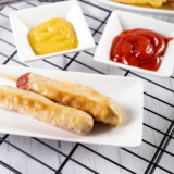 Alt Text: Crispy homemade corn dogs fresh from the air fryer with dipping sauces on the side.