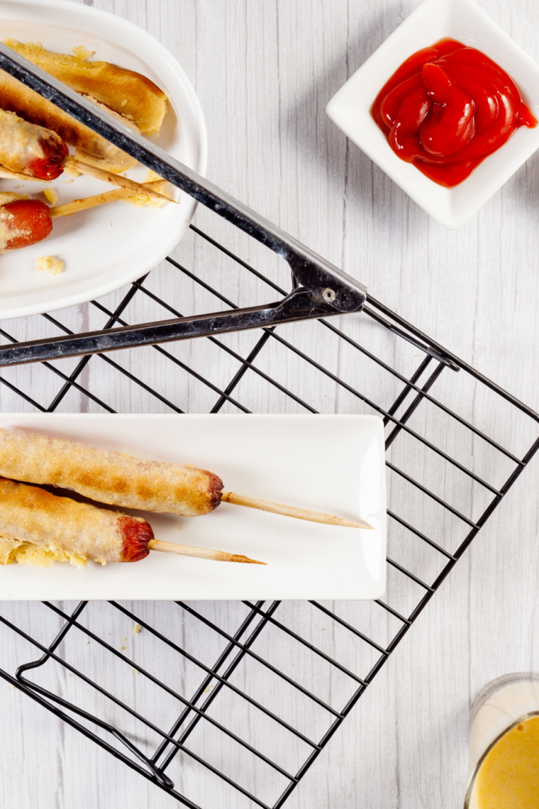 Air fryer corn dogs with golden cornbread coating, served hot on a plate with ketchup.