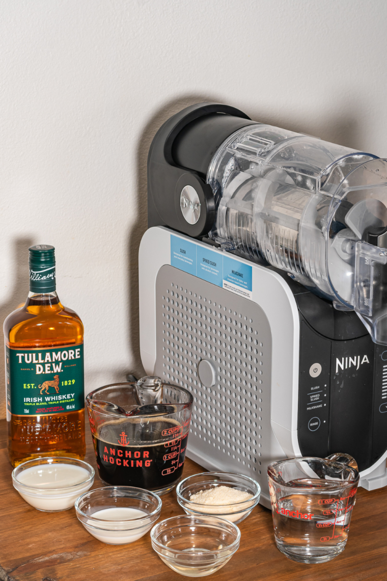 Blender filled with coffee, whiskey, milk, half and half, simple syrup, water, and ice cream mix being stirred smooth.