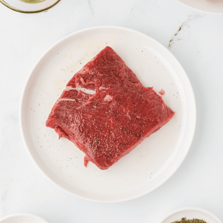 Raw steaks placed in a resealable bag with marinade being poured over them.