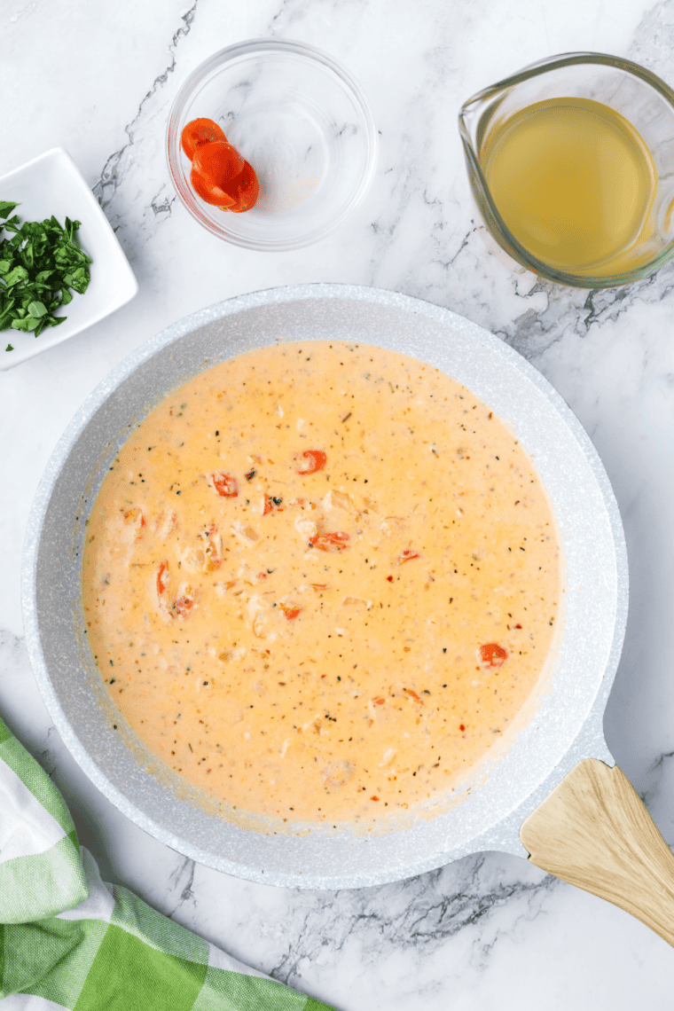 Whisking butter and flour roux, adding chicken broth and heavy cream until thickened