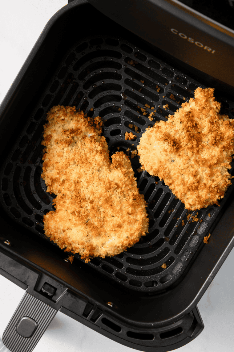 Golden, crispy panko-coated air fryer haddock served on a plate with lemon wedges and garnish.