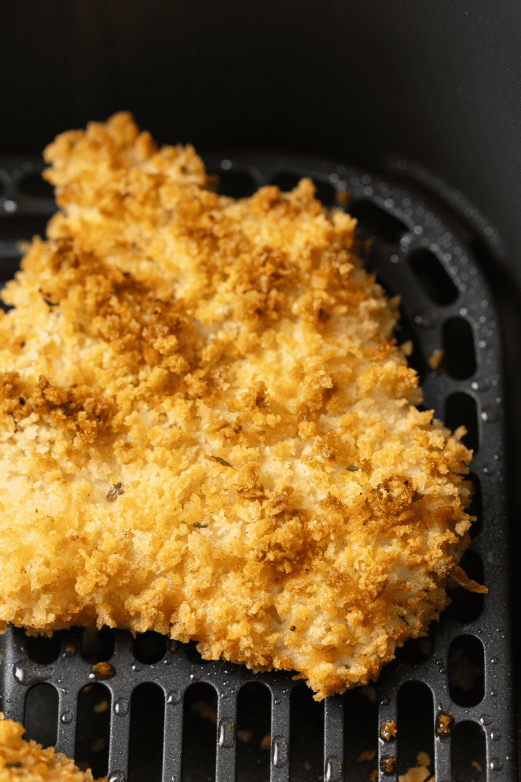 Golden crispy panko-coated haddock served on a plate with lemon wedges and fresh garnish.
