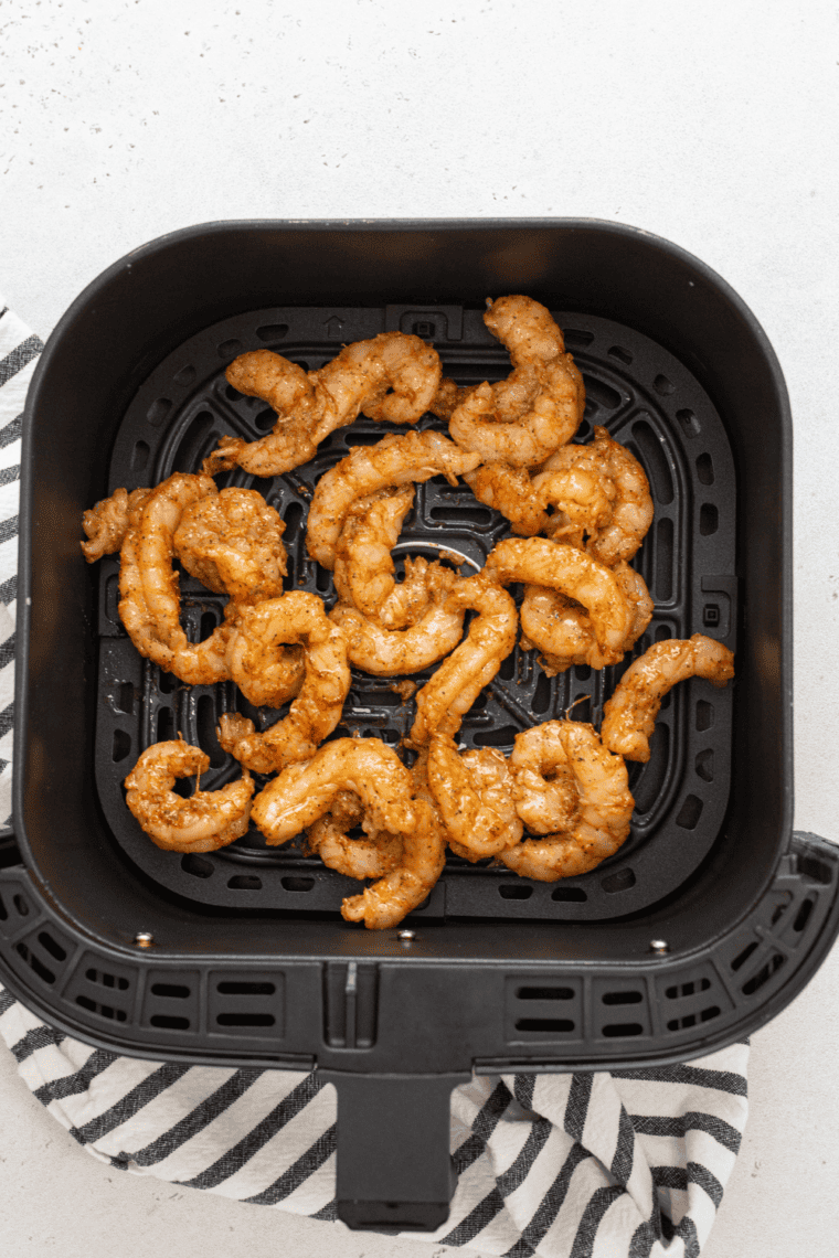 Shrimp cooking in an air fryer basket, golden and sizzling.