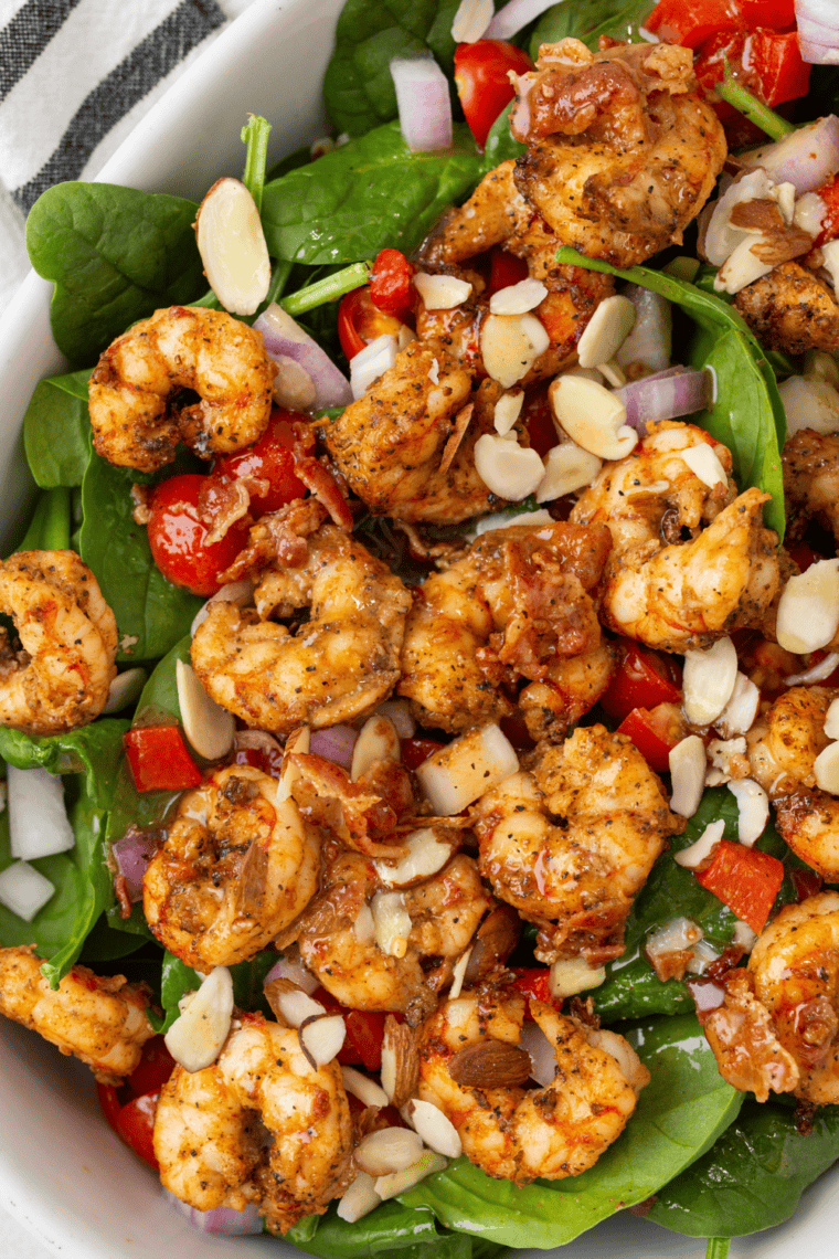 Air fryer shrimp served on fresh spinach salad with roasted red peppers and light dressing.