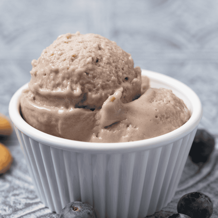 Creamy blueberry gelato scooped into a bowl and topped with fresh blueberries.