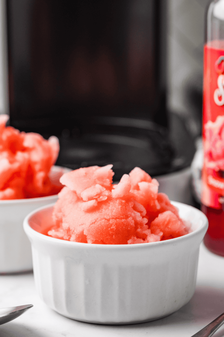 Bright red Cherry Italian Ice in a clear glass, smooth and icy texture, garnished with fresh cherries.
