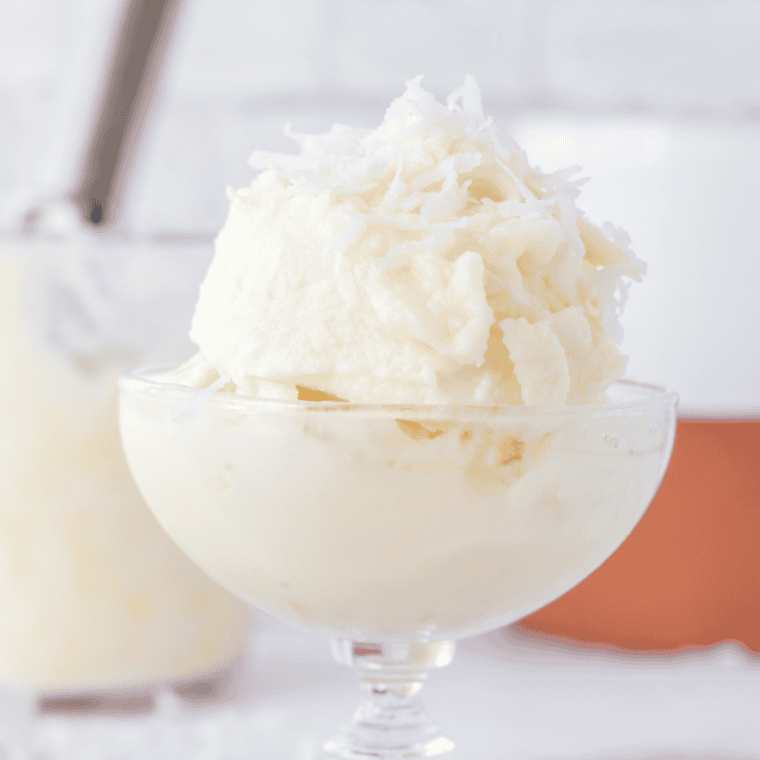 Creamy coconut gelato scooped into a bowl, topped with shredded coconut.