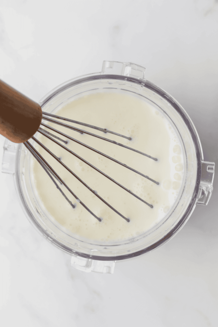 Whisking whole milk, heavy cream, sugar, and vanilla in a mixing bowl.