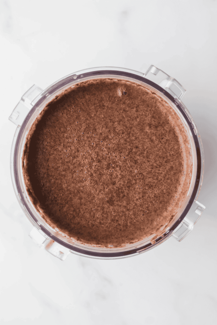 Pouring chilled mixture into Ninja Creami pint container for freezing.