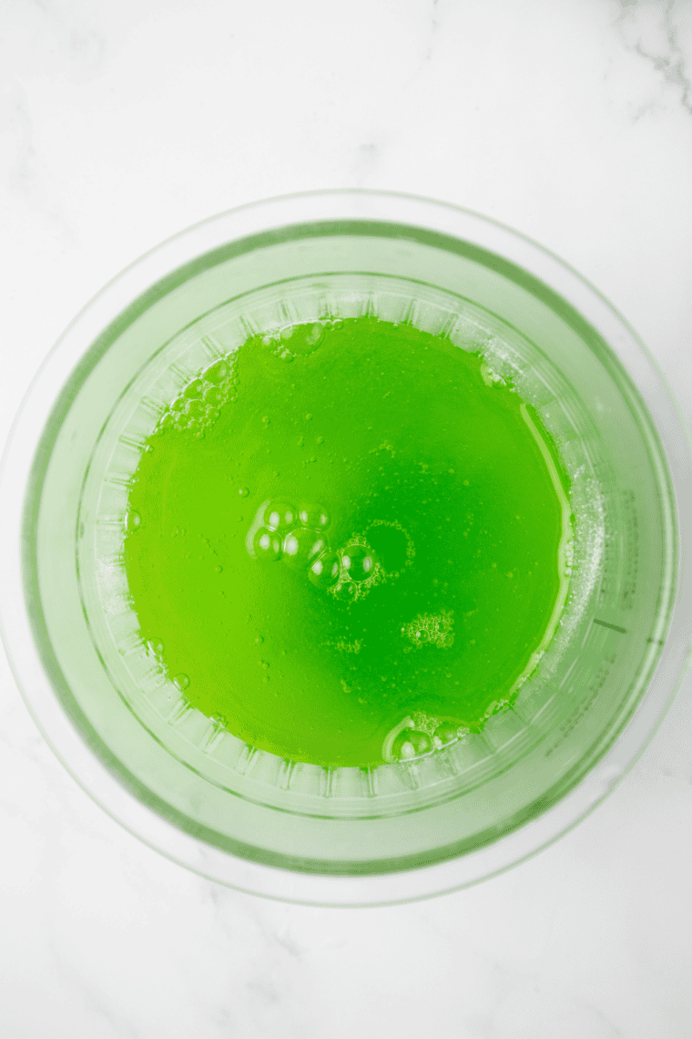 Mixing water, sugar, and syrup in a Ninja Creami pint container before freezing.