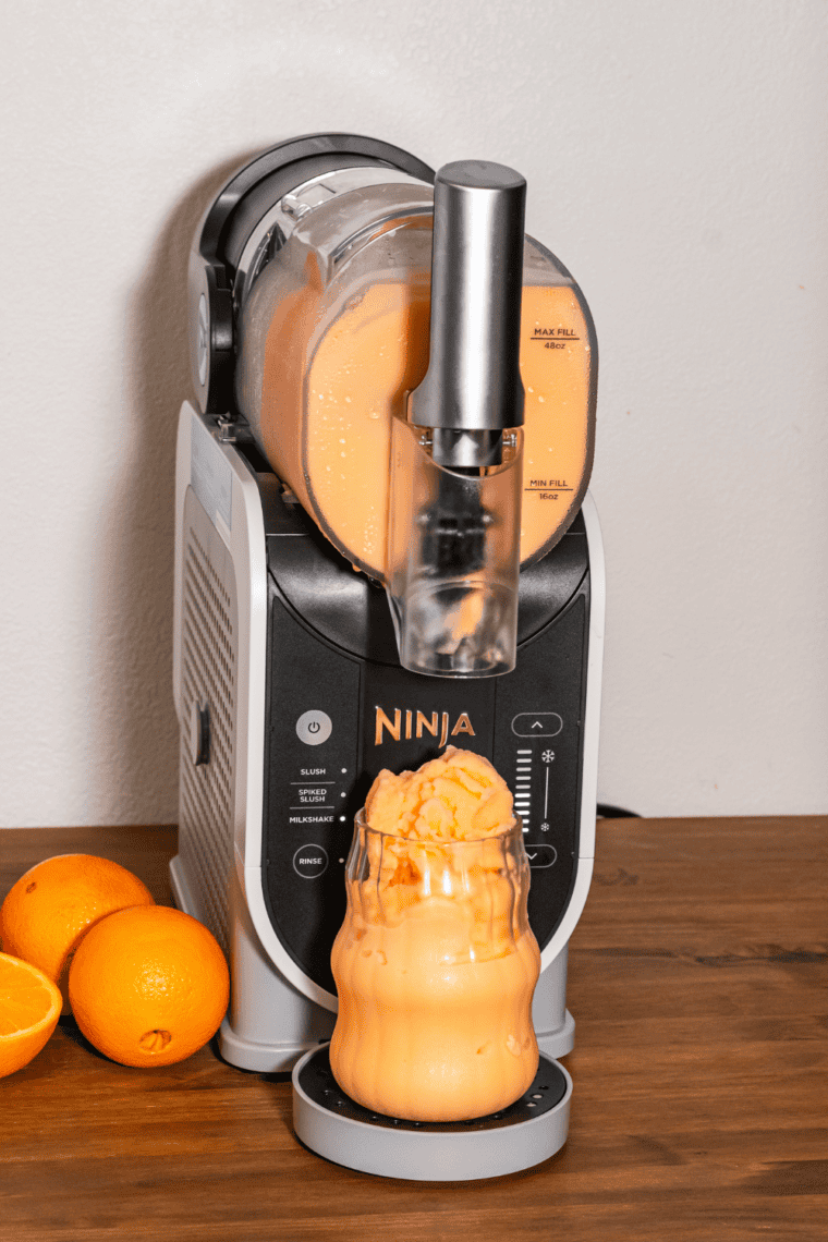 Ninja Slushi cup filled with orange soda, Dirty soda, and creamy Coffeemate ready for blending.