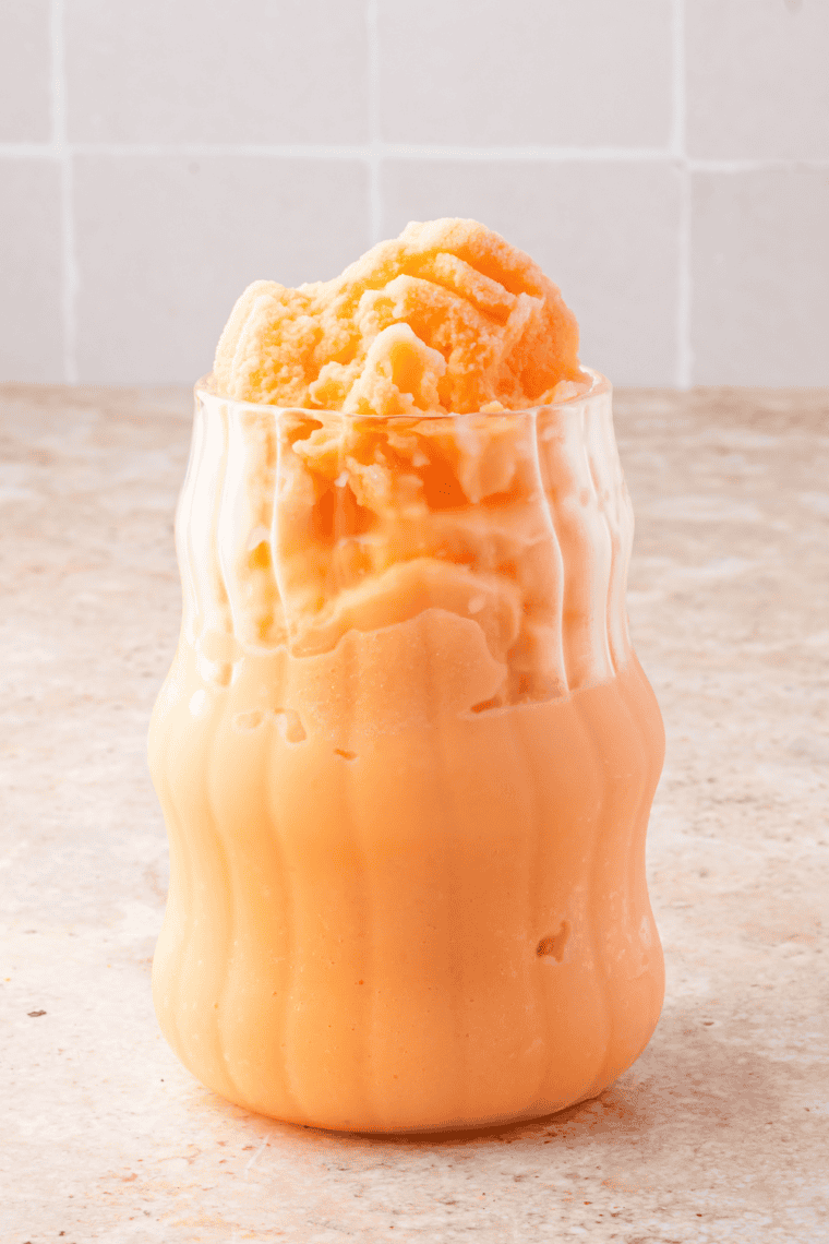 Icy Ninja Slushi frozen Dirty Orange Soda served in a tall glass with straw, garnished with an orange slice and syrup drizzle.