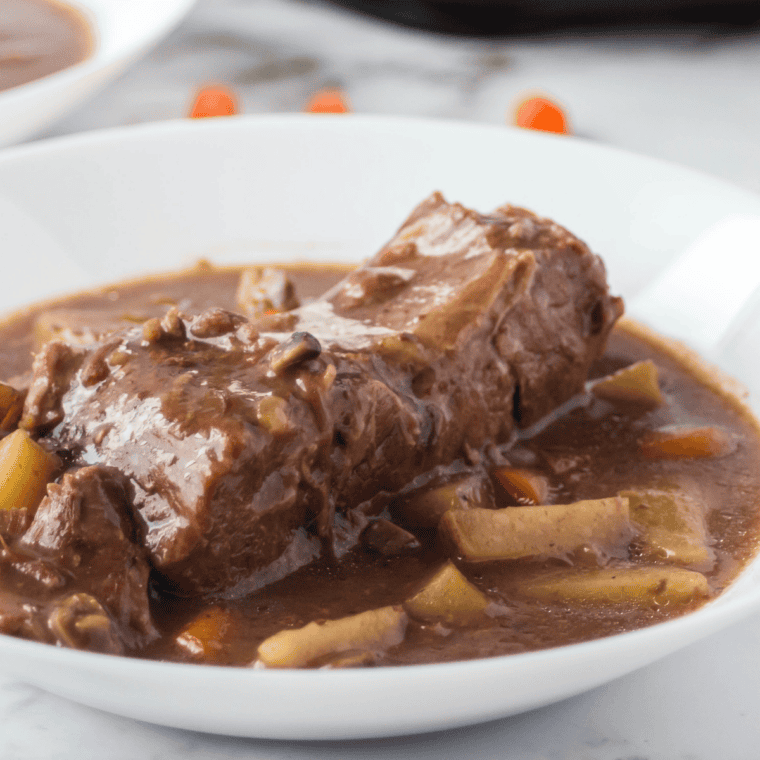 Sliced beef sirloin tip roast served with vegetables and mushroom gravy on plate.