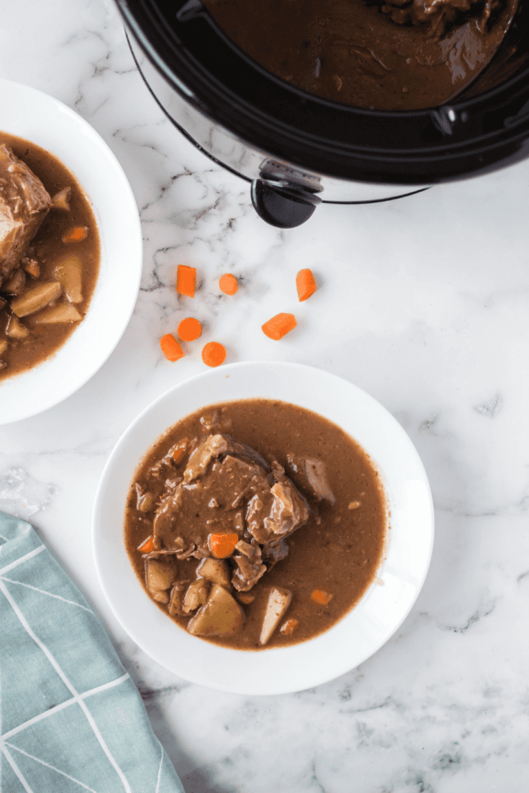 Sliced slow cooker beef sirloin tip roast with carrots, potatoes, and rich mushroom gravy.
