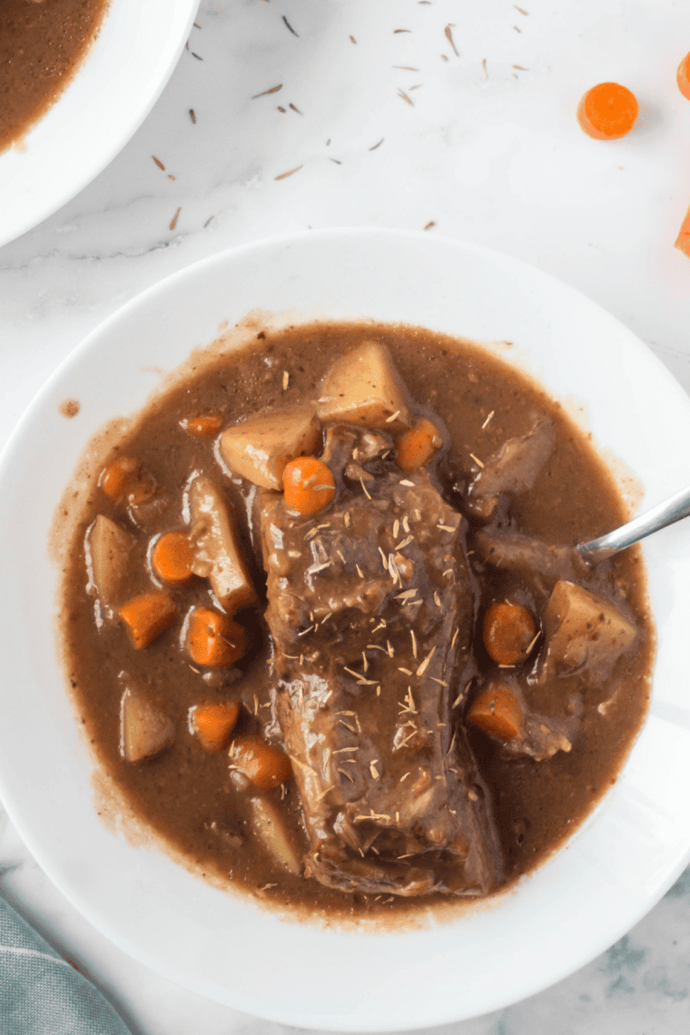 Sliced slow cooker beef sirloin tip roast served with carrots, potatoes, and rich mushroom gravy.