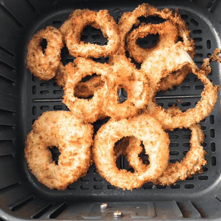 Crispy golden onion rings on a plate with tartar sauce for dipping.