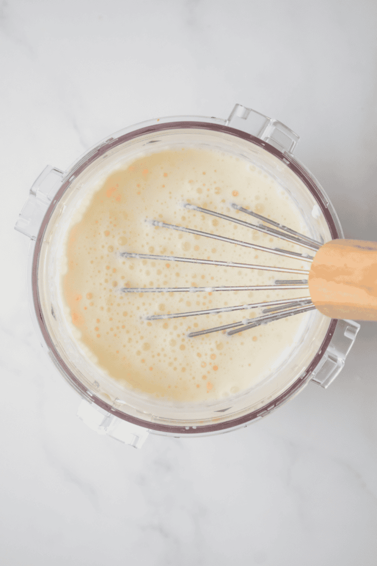 Mixing whole milk, heavy cream, sugar, and vanilla for coconut ice cream base.
